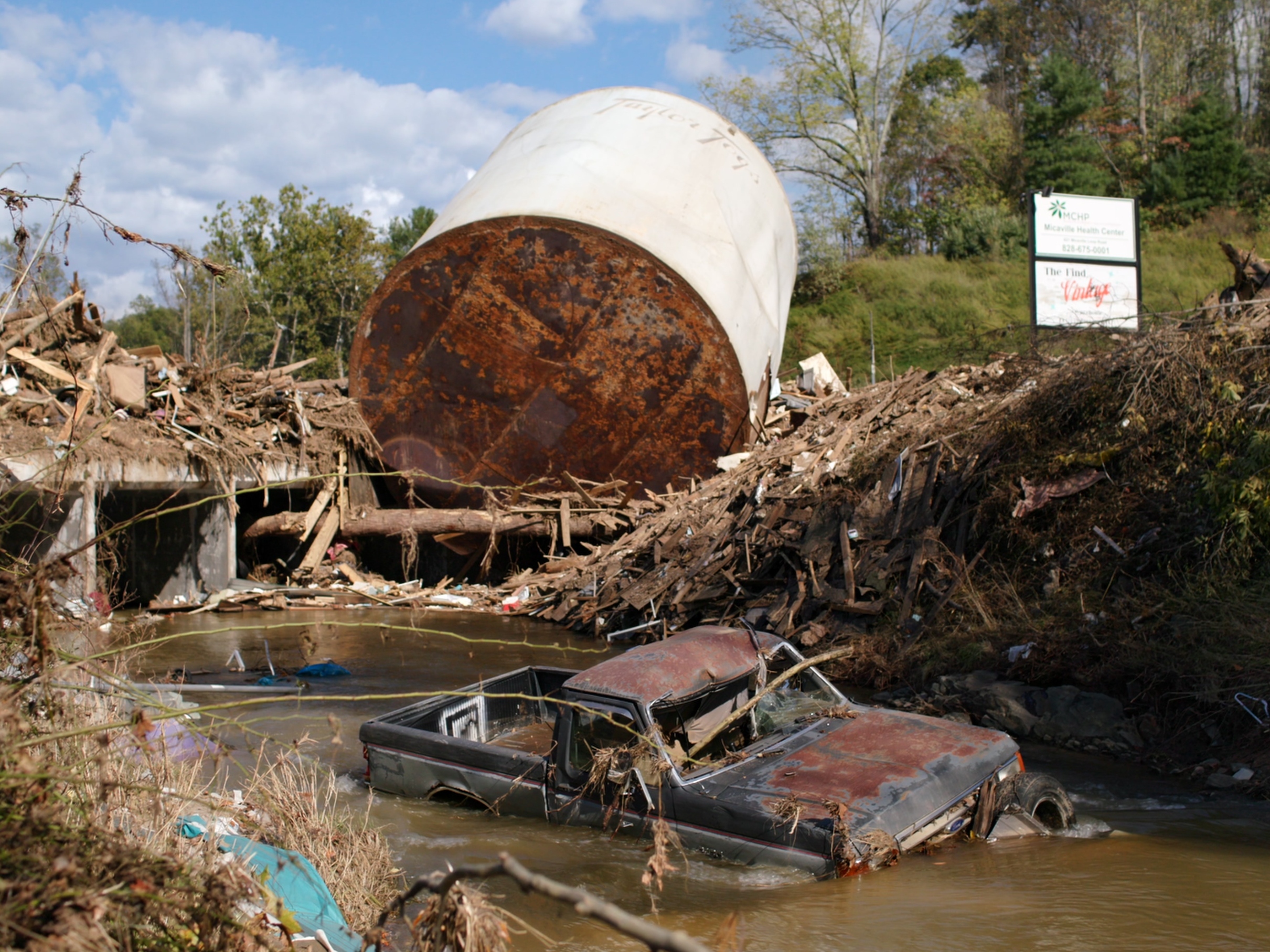 caption: A truck is stuck in water and mud following flooding from Hurricane Helene in western North Carolina.
