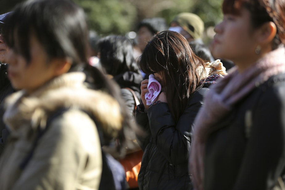 caption: People mourn for victims of the March 11, 2011 earthquake and tsunami, in Tokyo, Tuesday, March 11, 2014.