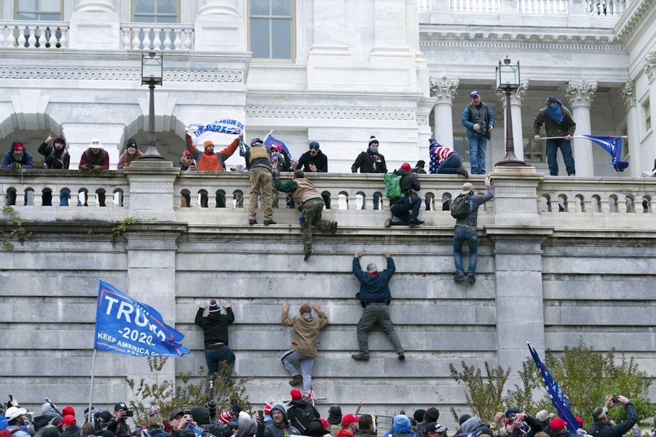 caption: In this Jan. 6, 2021 file photo rioting supporters of President Donald Trump climb the west wall of the the U.S. Capitol in Washington. Historians say Trump’s legacy and his electoral undoing will be largely shaped by rhetoric aimed at stirring his largely white base that tugged at the long-frayed strands of race relations in America. 