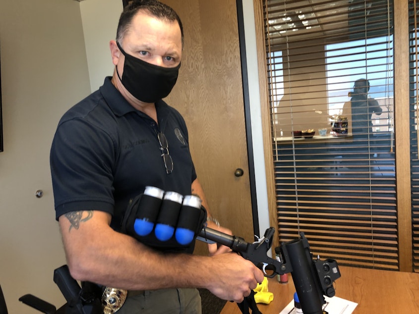 caption: Tim Collings with the Everett Police Department demonstrates use of a launcher that fires 40mm non-lethal rounds. They've stopped using the launchers in the wake of a new state ban on large-caliber ammunition.  