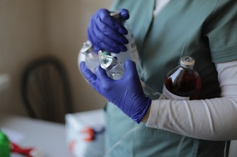 caption: A nurse holds bottles of medications. The Lviv hospital had about three weeks of reserves on site.