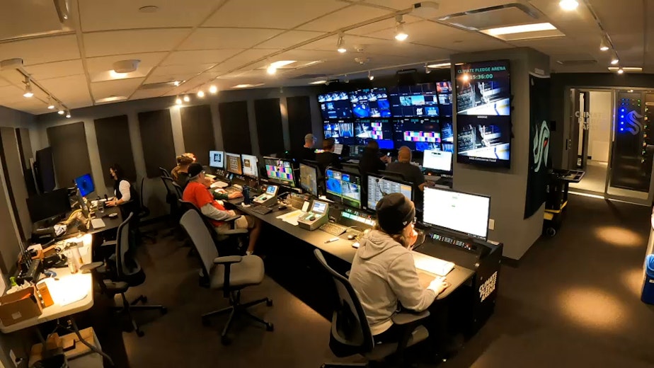 caption: The Seattle Kraken's video crew watches a game from the control room. Everything they collect will eventually be filed digitally by the team's librarians, Gina Rome and Ashley Hufford.