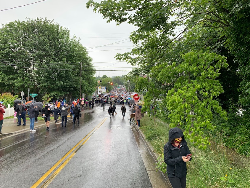 caption: Marchers approach South College Street as they proceed on 23rd Avenue South. The silent protest organized by Black Lives Matter Seattle-King County drew thousands.