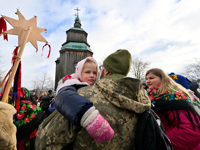 caption: A Ukrainian serviceman holds his daughter as they take part in Christmas celebrations in the village of Pyrogove, near Kyiv on Monday.