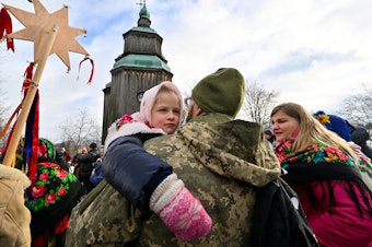 caption: A Ukrainian serviceman holds his daughter as they take part in Christmas celebrations in the village of Pyrogove, near Kyiv on Monday.