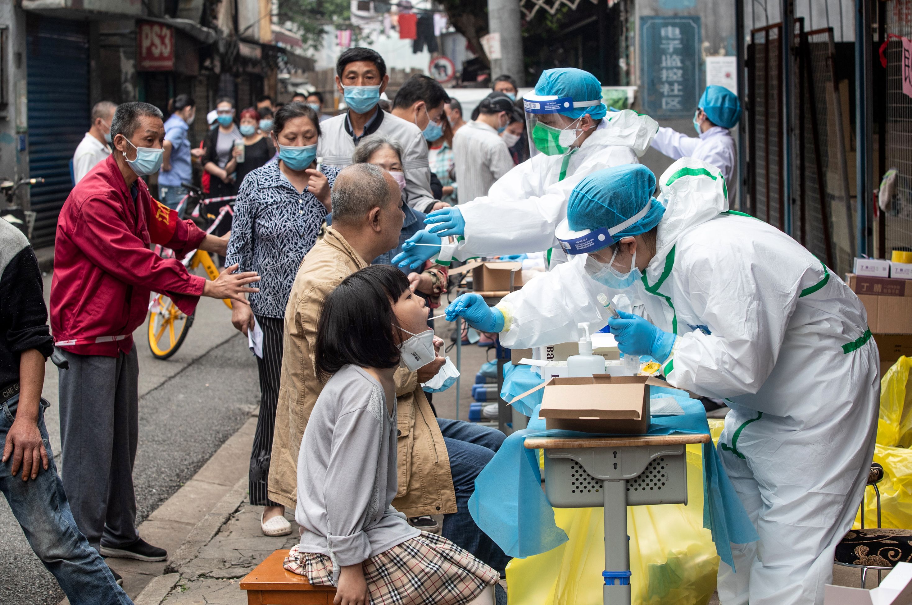 caption: Medical workers take swab samples from residents to be tested for the COVID-19 coronavirus, in a street in Wuhan in China's central Hubei province on May 15, 2020.  (STR/AFP via Getty Images)