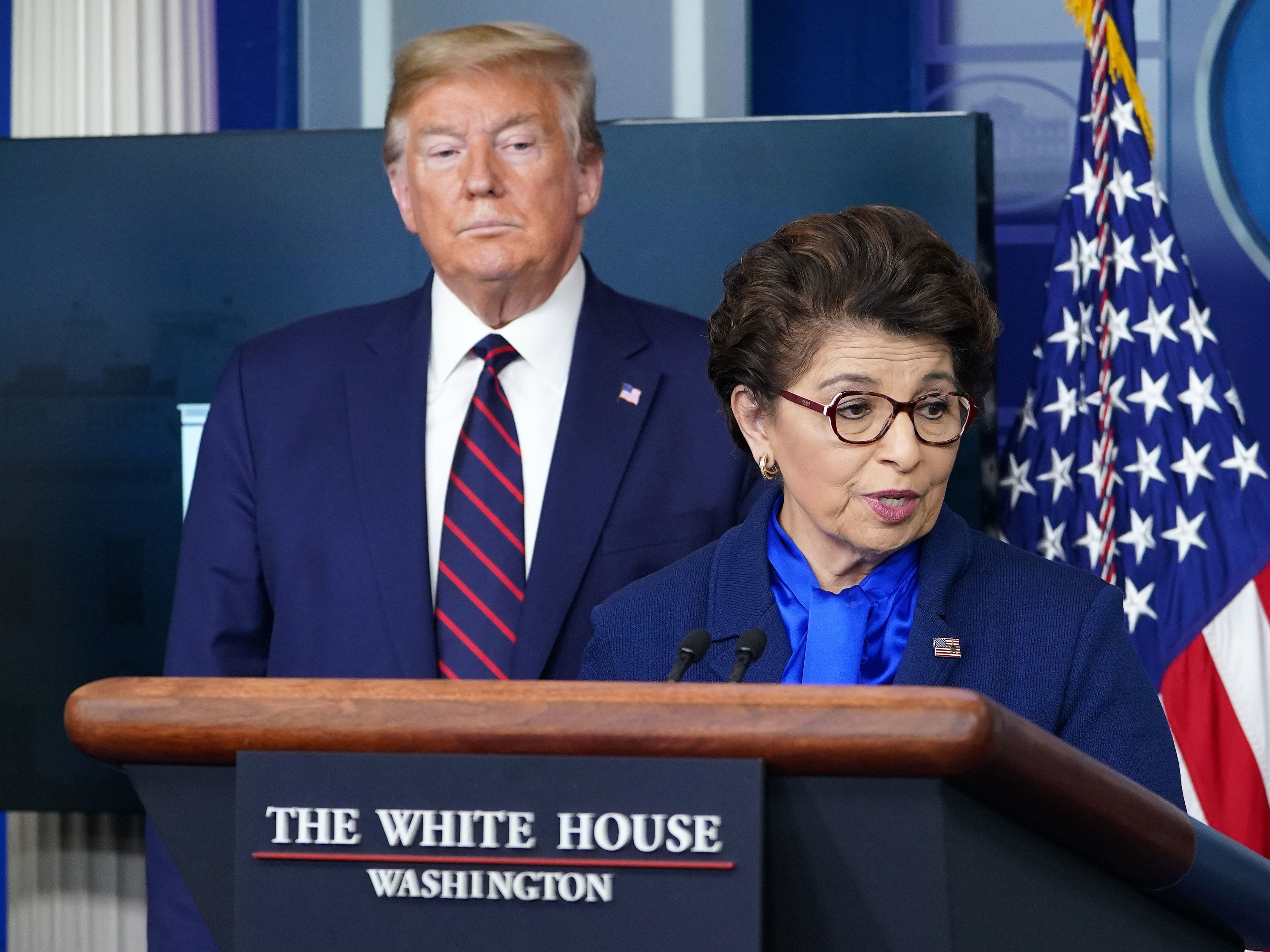 caption: Small Business Administration head Jovita Carranza speaks during a briefing on the coronavirus at the White House on April 2 as President Trump looks on.