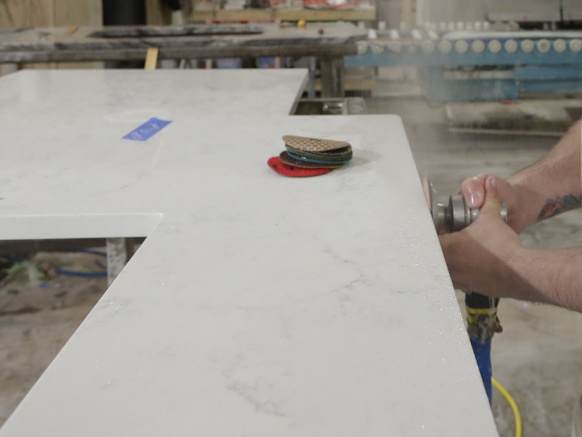caption: A worker polishes the edge of a kitchen countertop cut from a slab of quartz, an "engineered stone" that can produce harmful silica dust when cut, ground or polished.