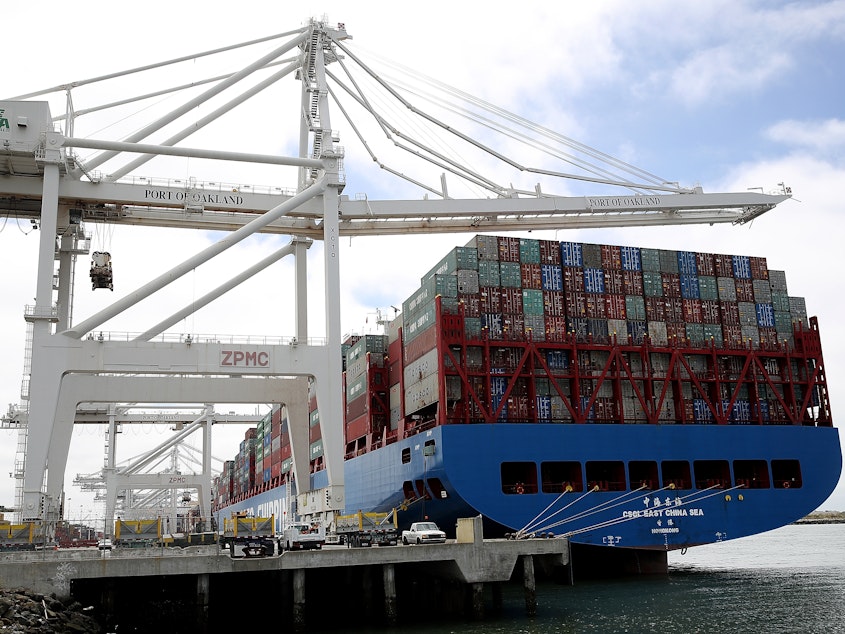 caption: A container ship sits in a berth at the Port of Oakland in California last year. President Trump announced additional tariffs on imports from China on Thursday.