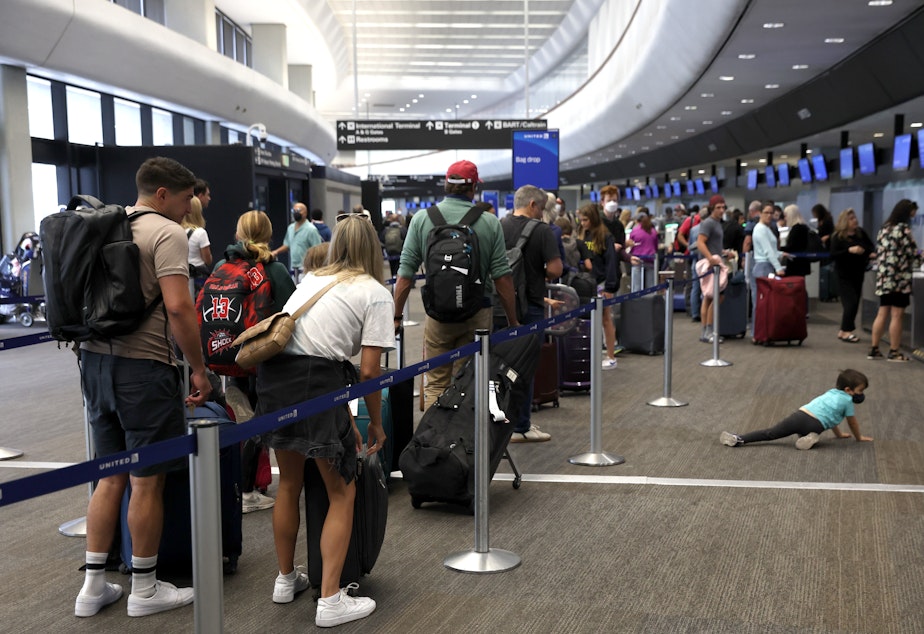 caption: Travelers line up to check in for United Airlines flights at San Francisco International Airport on July 1, 2022 in San Francisco, Calif. This summer is expected to be a record for air travel.