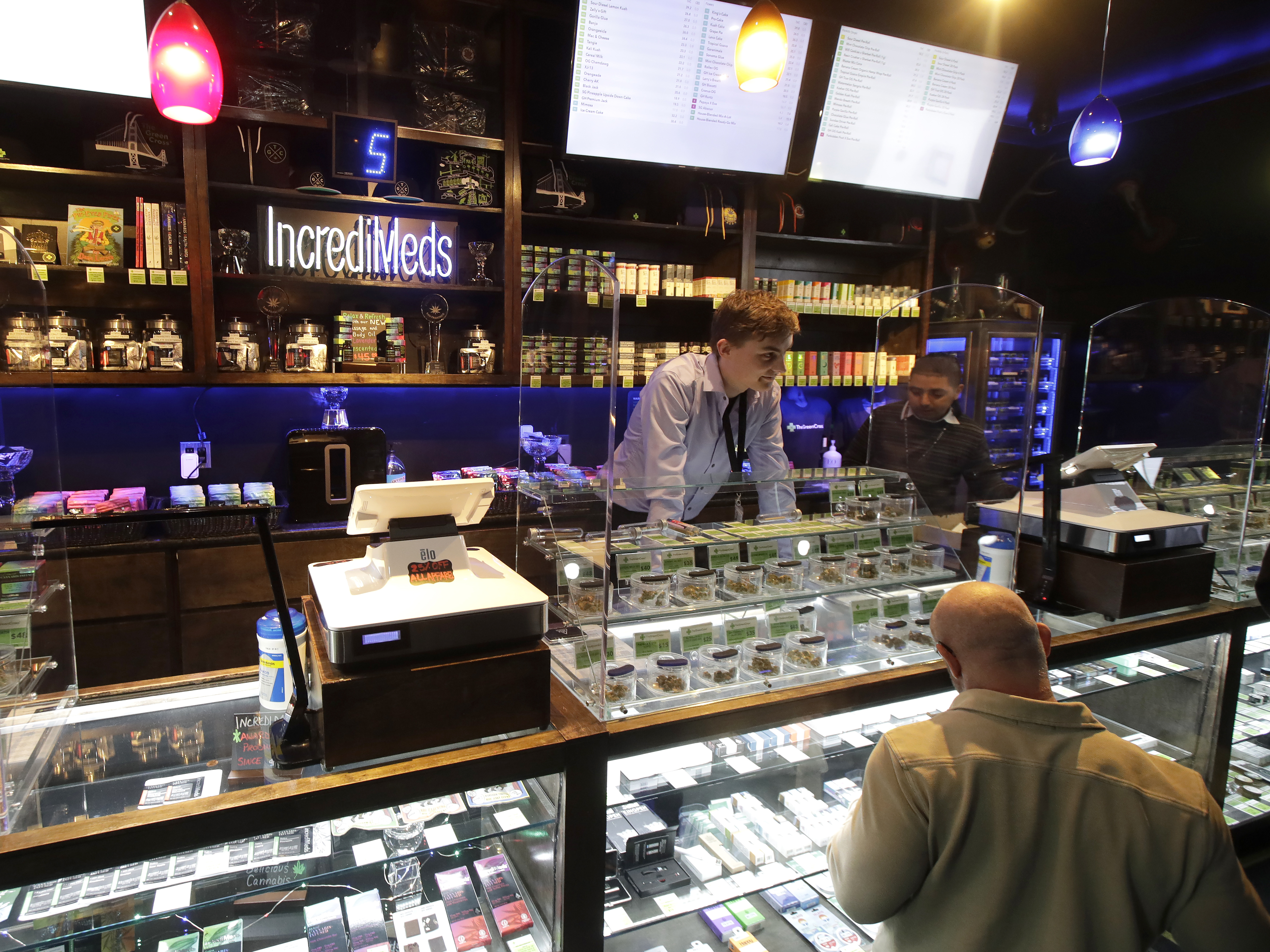 caption: Budtenders at The Green Cross cannabis dispensary help customers in San Francisco, Wednesday, March 18, 2020.