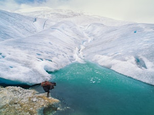 caption: A barefoot porter totes a load for an expedition visiting one of the remaining glaciers near the equator, 16,000 feet high on the highest peak in Papua, Indonesia.