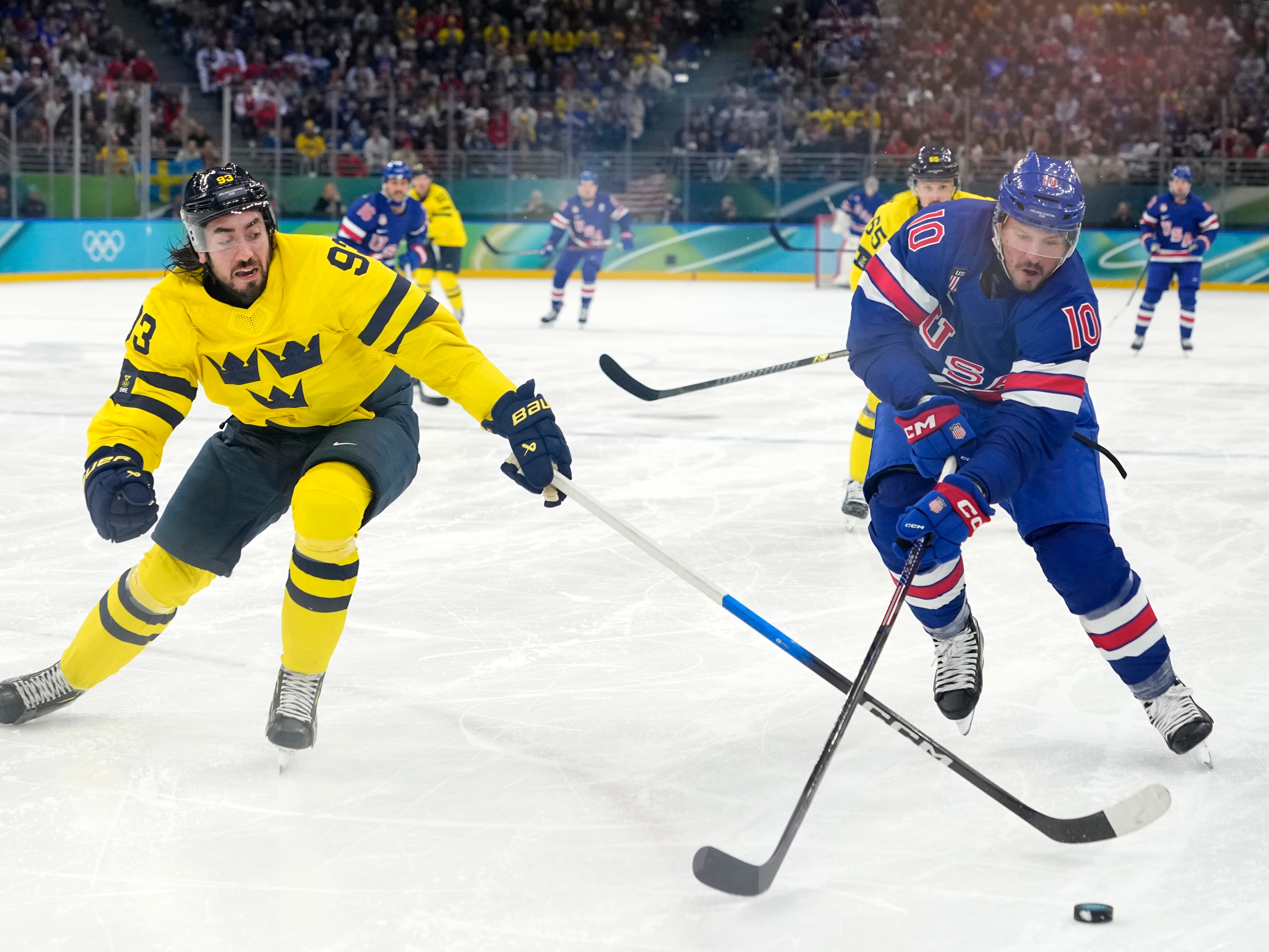 caption: Sweden's Mika Zibanejad (93) and United States' JT Miller (10) chase the puck during the third period of a men's ice hockey quarterfinal game at the 2026 Winter Olympics, in Milan, Italy.