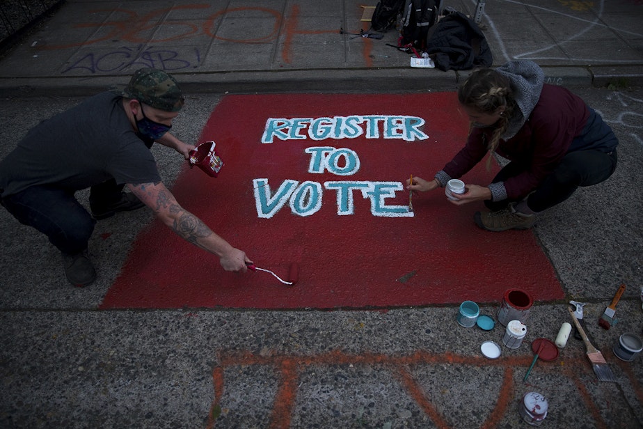 caption: Jared, left, and Jessika, right, paint a Register to Vote street mural inside the Capitol Hill Autonomous Zone, CHAZ, or Capitol Hill Occupied Protest, CHOP, on Saturday, June 13, 2020, in Seattle.