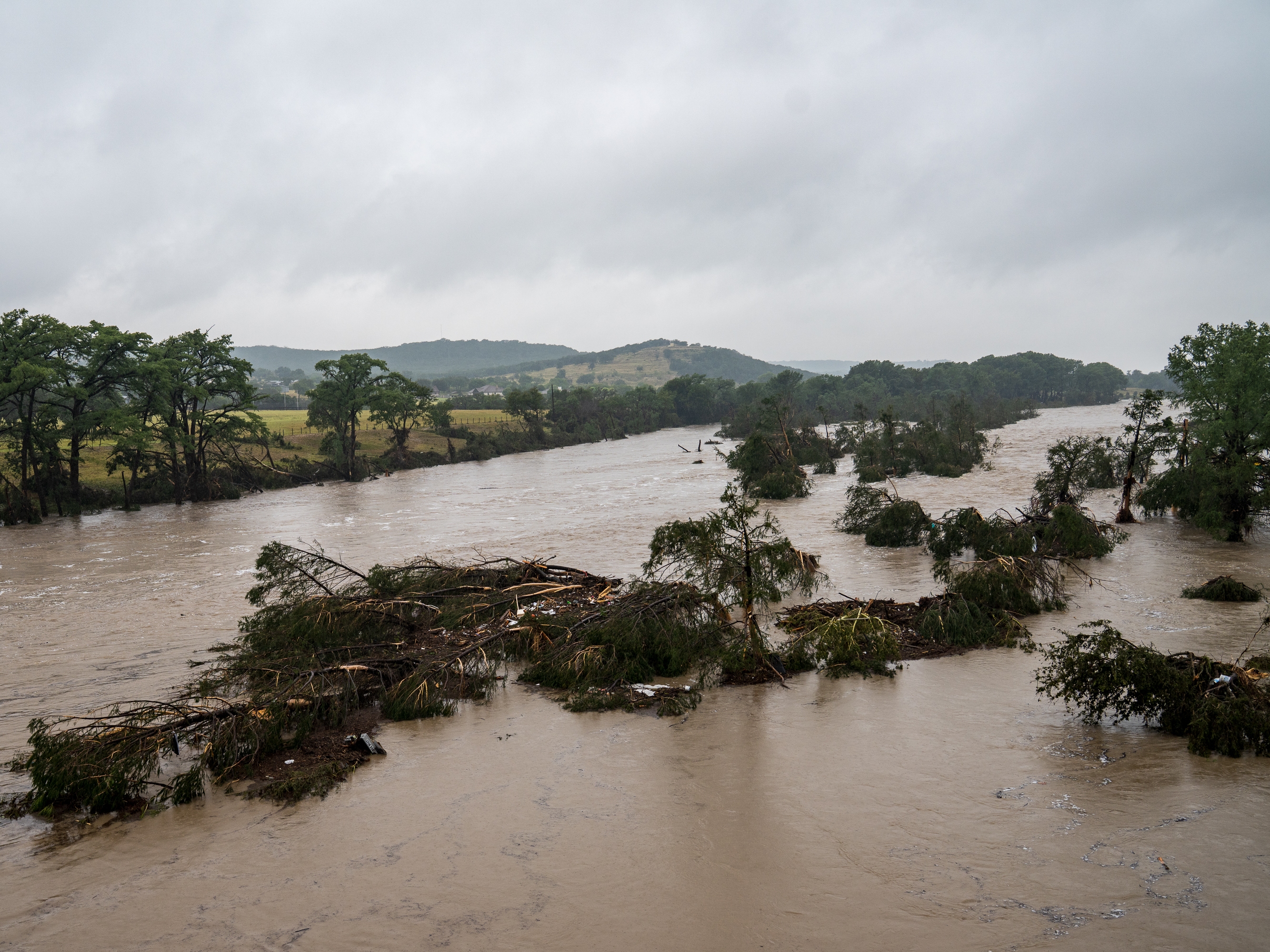 caption: Trees emerge from flood waters along the Guadalupe River on Friday in Kerrville, Texas. Heavy rainfall caused flooding along the Guadalupe River in central Texas with multiple fatalities reported.