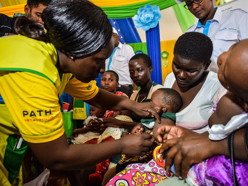 caption: A health worker vaccinates a Kenyan child with the world's first malaria vaccine. Kenya has given at least one dose to 300,000 children so far.