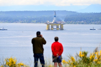 caption: John and Linda Beatty of Seattle watch Foss Maritime tugs pull the Polar Pioneer oil rig south past Discovery Park toward the Port of Seattle's Terminal 5 on May 14, 2015.