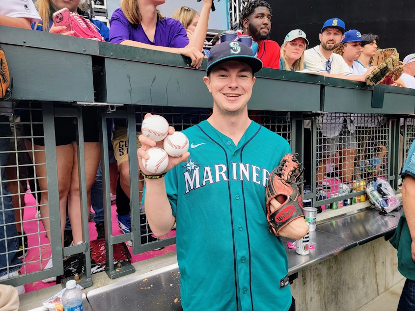 caption: Patrick O'Neal shows off his three homerun balls he snagged at the Home Run Derby in Seattle on Monday, July 10, 2023.