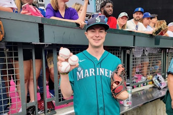 caption: Patrick O'Neal shows off his three homerun balls he snagged at the Home Run Derby in Seattle on Monday, July 10, 2023. 