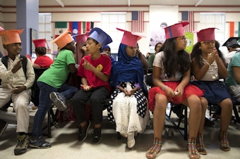 caption: Graduates of the International Rescue Committee summer school program, including Ikran Osman, 5, center, sit in the cafeteria before a graduation ceremony on Thursday, August 3, 2017, at Showalter Middle School in Tukwila. 
