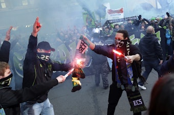 caption: Seattle Sounders fans burn a Portland Timbers scarf during the 'March to the Match' before an MLS soccer match, Saturday, March 16, 2013, in Seattle.