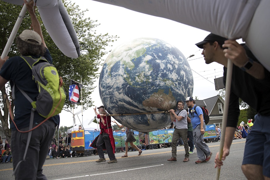 caption: Parade-goers carry a blow-up planet Earth while marching in the Fremont Solstice Parade.