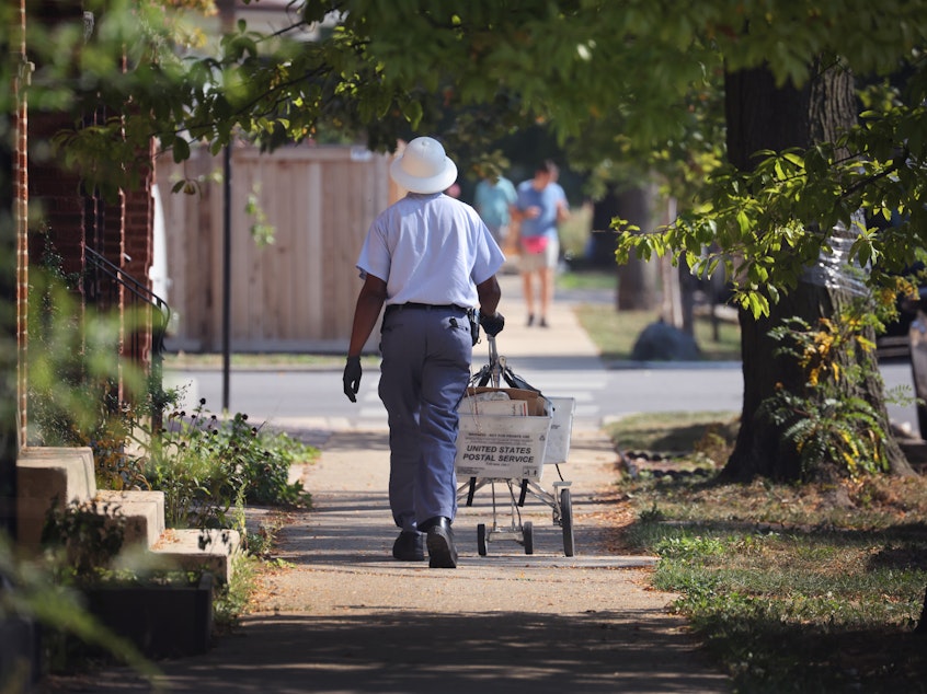 caption: A postal worker delivers mail on October 1, 2021 in Chicago, Illinois.