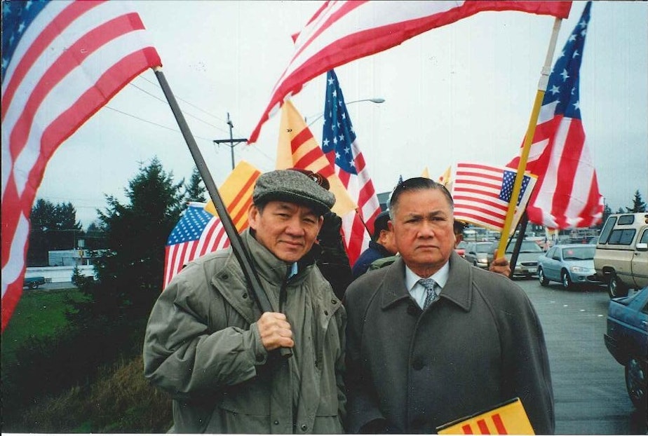 caption: Thanh's father, Duc Tan, holds the American flag and stands next to Dr. Dung Nguyen, president of the Vietnamese Community of Pierce County, at a political rally in this undated photo. 