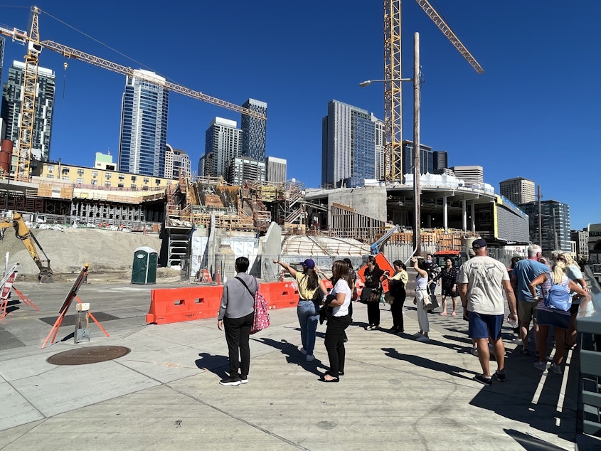 caption: Tourists try to figure out how to get to the Pike Place Market from the waterfront. Once the “Salish Steps” in the background are completed, the route will be dramatically simplified.