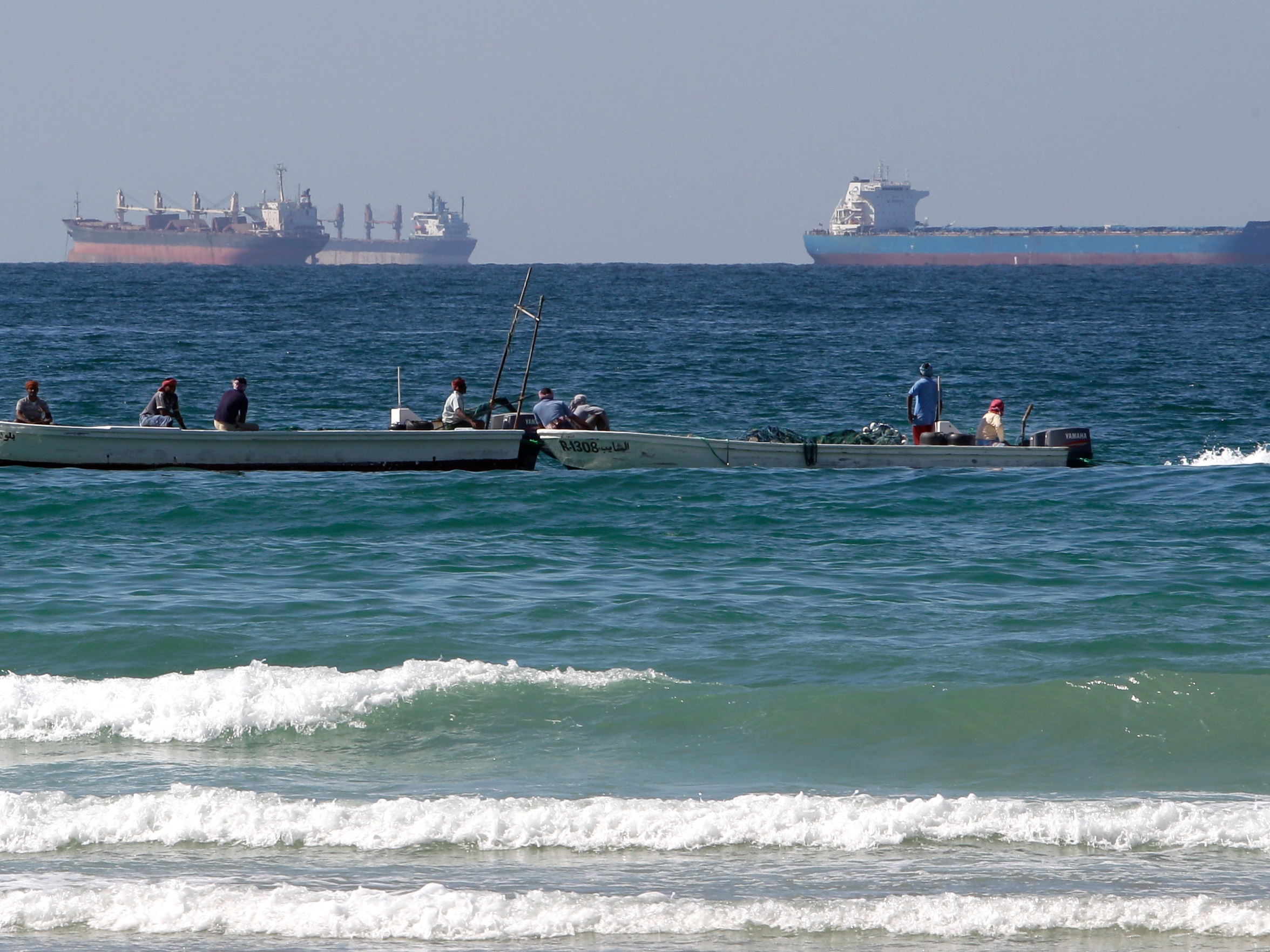 caption: Fishermen work in front of oil tankers south of the Strait of Hormuz on Jan. 19, 2012, offshore of the town of Ras Al Khaimah in United Arab Emirates.