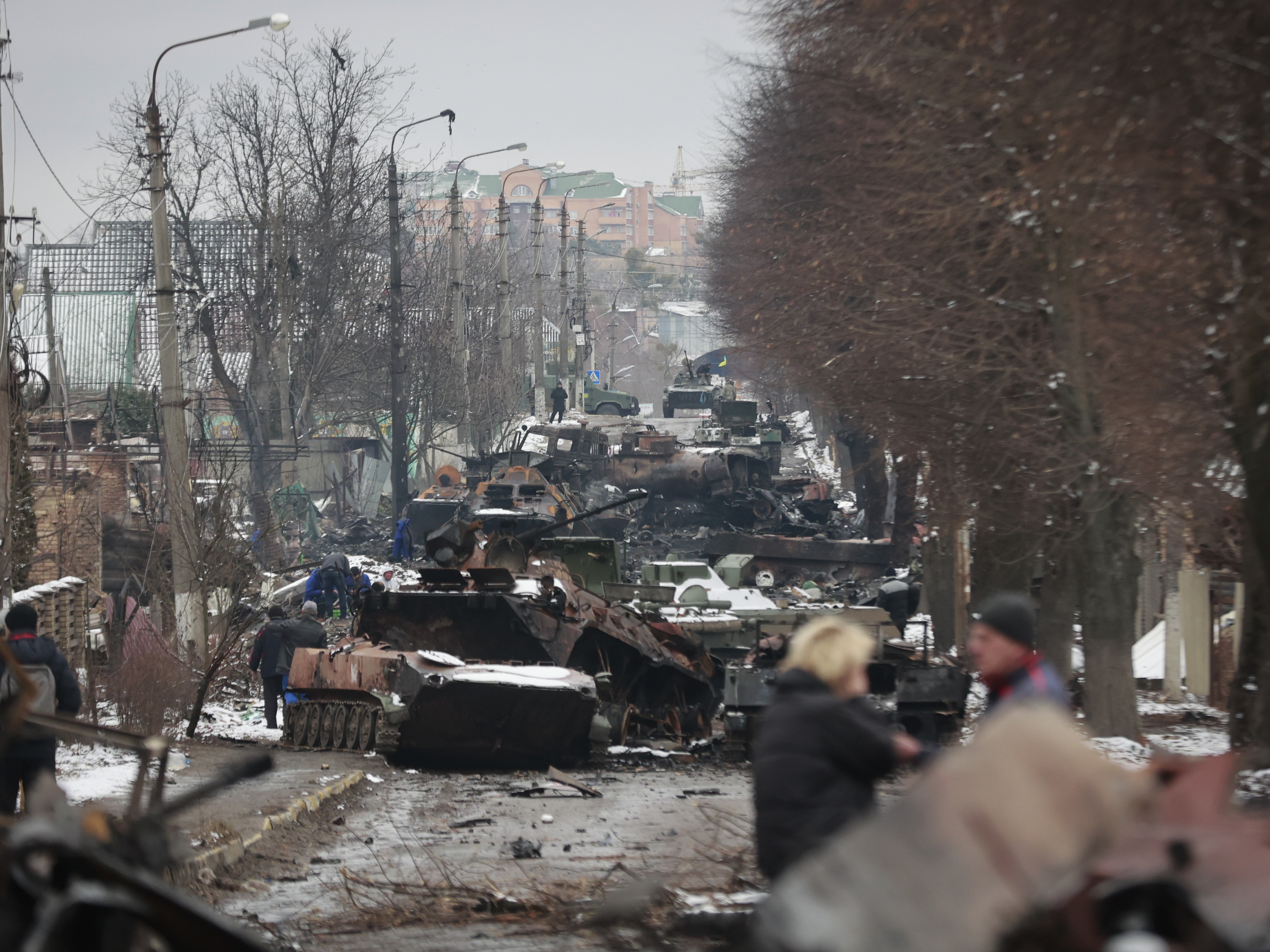 caption: People look at the gutted remains of Russian military vehicles on a road in the town of Bucha, close to Ukraine's capital, Kyiv, on Tuesday.