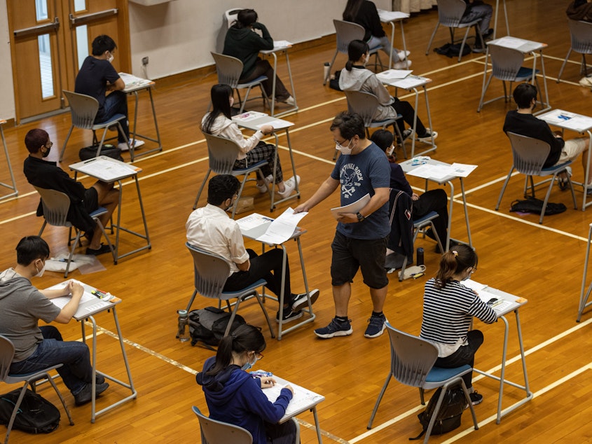 caption: An invigilator distributes papers to students taking the Hong Kong Diploma of Secondary Education exams on April 22, in Hong Kong.