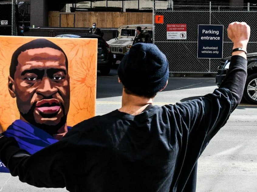 caption: An demonstrator holds a portrait of George Floyd in March 2021 outside the Hennepin County Government in Minneapolis, where the trial of former Minneapolis Police Department officer Derek Chauvin in Floyd's killing was under way.