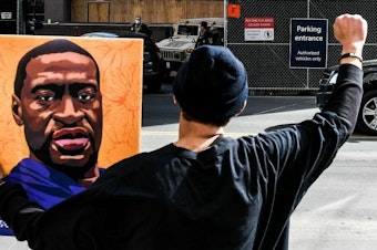 caption: An demonstrator holds a portrait of George Floyd in March 2021 outside the Hennepin County Government in Minneapolis, where the trial of former Minneapolis Police Department officer Derek Chauvin in Floyd's killing was under way.