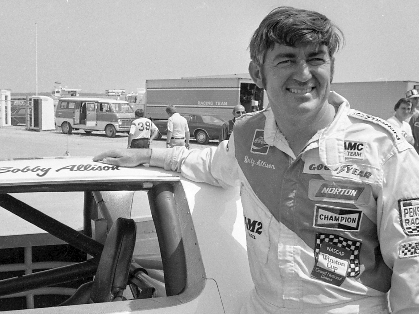 caption: Bobby Allison stands beside his car and talks with the press after winning the pole position during qualifying for the 500 mile grand national stock car race at Pocono Raceway, Aug. 2, 1975, in Long Pond, Pa.
