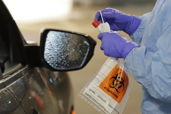 caption: A nurse at a drive up COVID-19 coronavirus testing station, set up by the University of Washington Medical Center in Seattle.