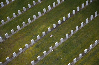caption: An American flag is shown between rows of headstones in the Veterans section on Thursday, March 1, 2018, at Evergreen Washelli Cemetery in Seattle. 