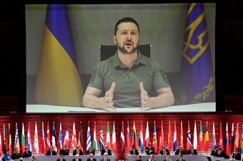 caption: Ukraine's President Volodymyr Zelenskyy appears on screen to speak at the opening of the 4th Summit of the Heads of State and Government of the Council of Europe on May 16. Ukraine announced on Friday that Zelenskyy will travel to Japan this weekend to attend the Group of Seven leading industrial nations' summit.