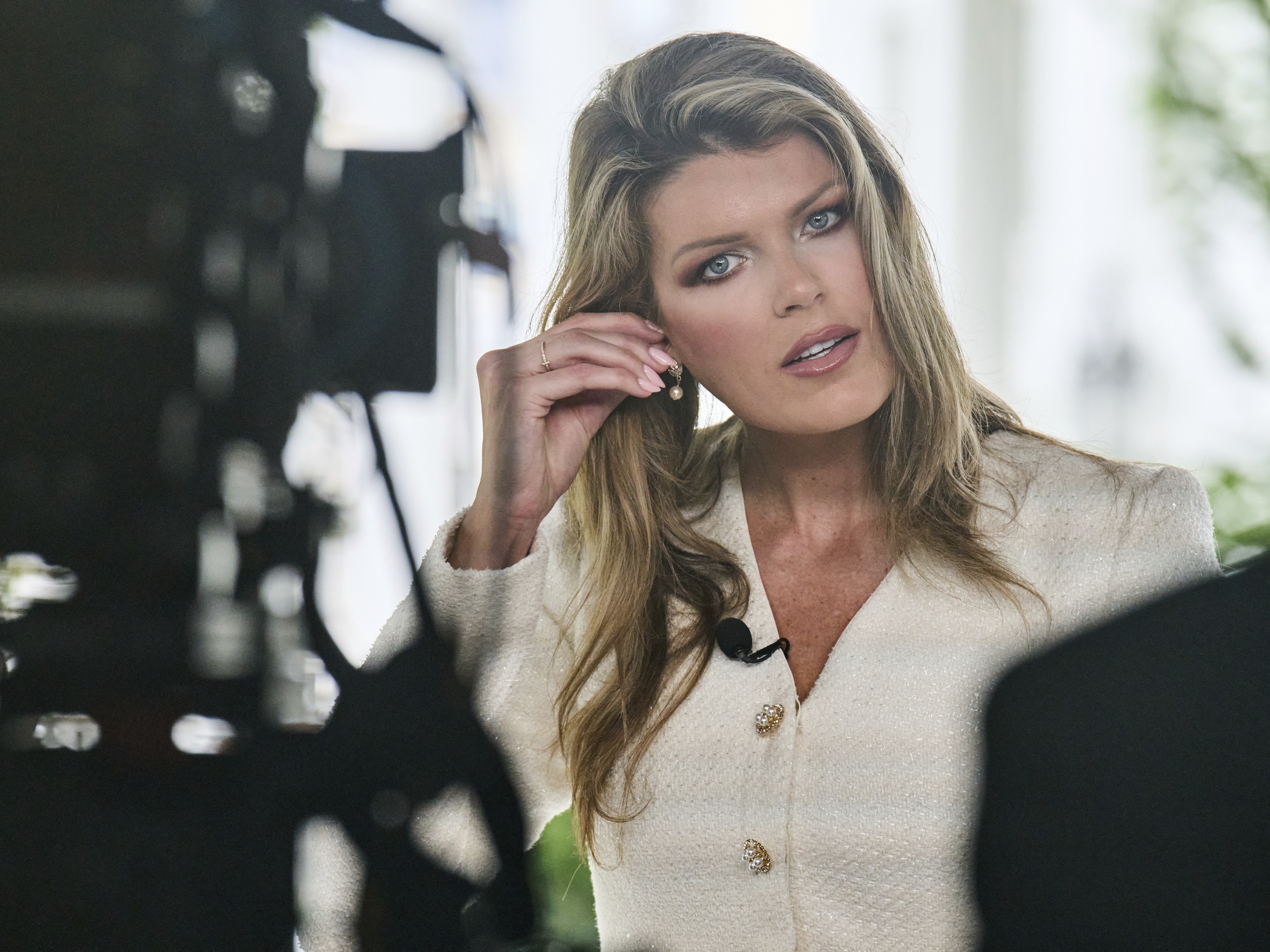caption: Lindsey Halligan, at the time special assistant to the president, fixes an earring at the end of an interview outside of the White House in August 2025, in Washington.