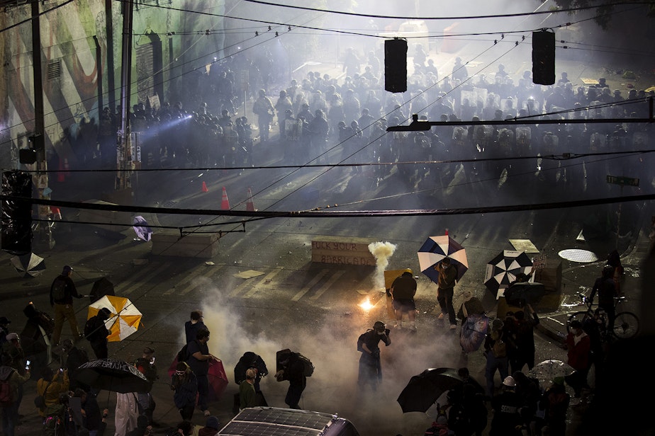 caption: Seattle police officers deployed tear gas, pepper spray, and flash-bang grenades on protesters shortly after midnight on Sunday June 7, 2020, in Capitol Hill. The next day, after a week of tense, nightly standoffs between demonstrators and a fortified line of police in riot gear, the police line moved out and the precinct windows were boarded up. Over the PA system, protest organizers called for a peaceful gathering and reiterated the overall goal: to defund the Seattle Police Department.