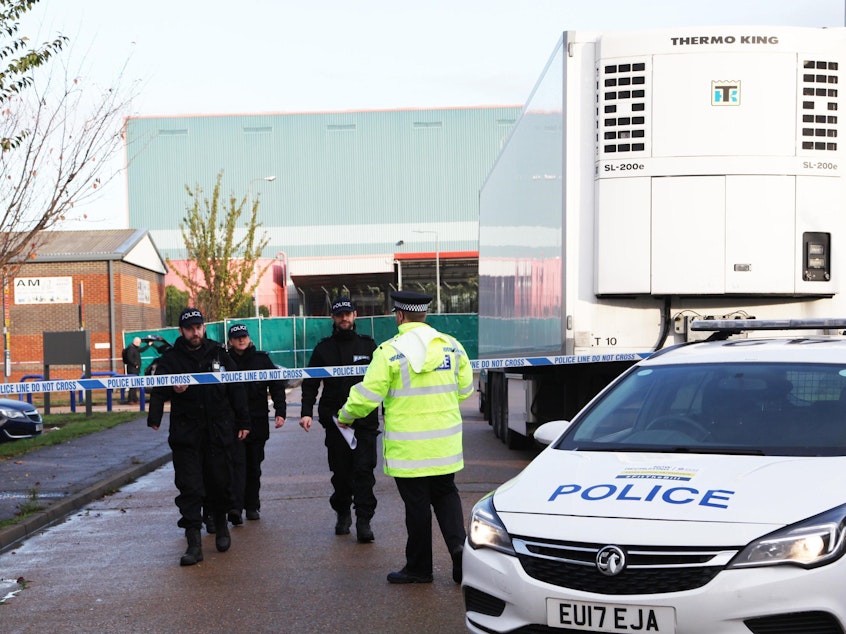 caption: Essex police officers at the scene where 39 bodies were found in the back of a truck on October 24.