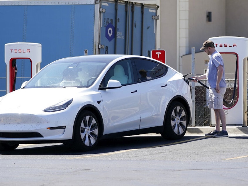 caption: A Tesla owner charges his vehicle in April 2021 at a charging station in Topeka, Kan.. Tesla reported 273 crashes involving partially automated driving systems, according to statistics released by U.S. safety regulators on Wednesday.