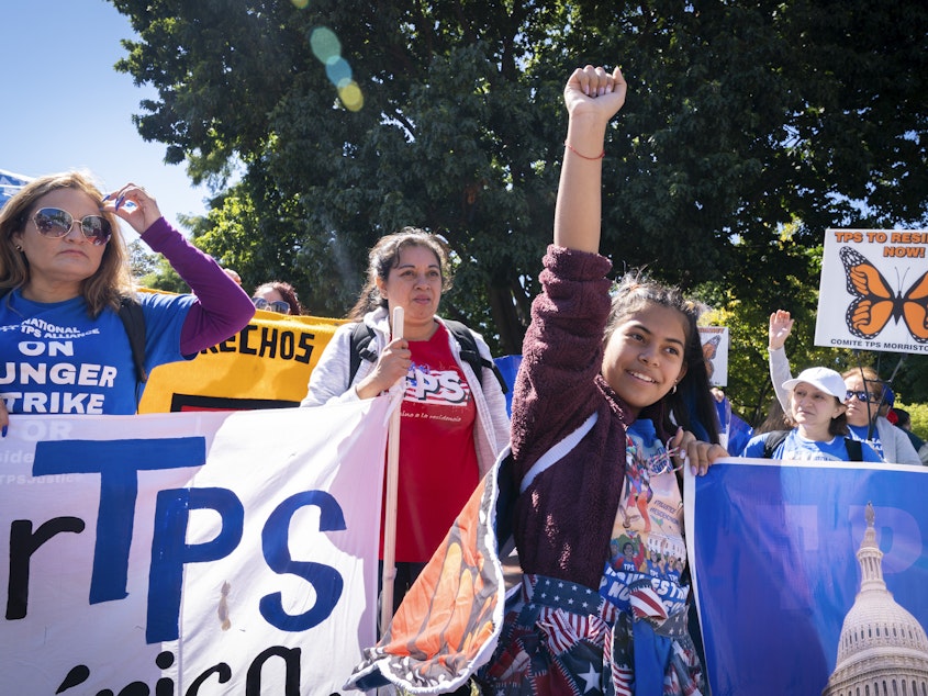 caption: Marilyn Miranda, 12, of Washington raises her hand up during a protest for an extension of the Temporary Protected Status in September 2022 in Washington, D.C.