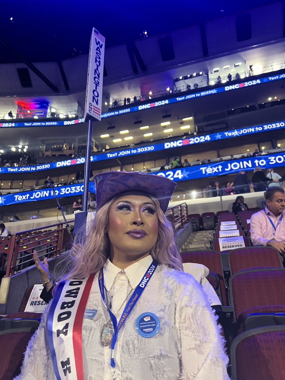 caption: Leiyomi Preciado, a Washington state delegate from Bremerton, poses at the Democratic National Convention on Aug. 19, 2024. She believes she's the first out transgender delegate from Washington state. Sitting in the convention center Monday, she wore a sash with the words "Cowboy Kamala" — a reference to the most recent Beyoncé album.
