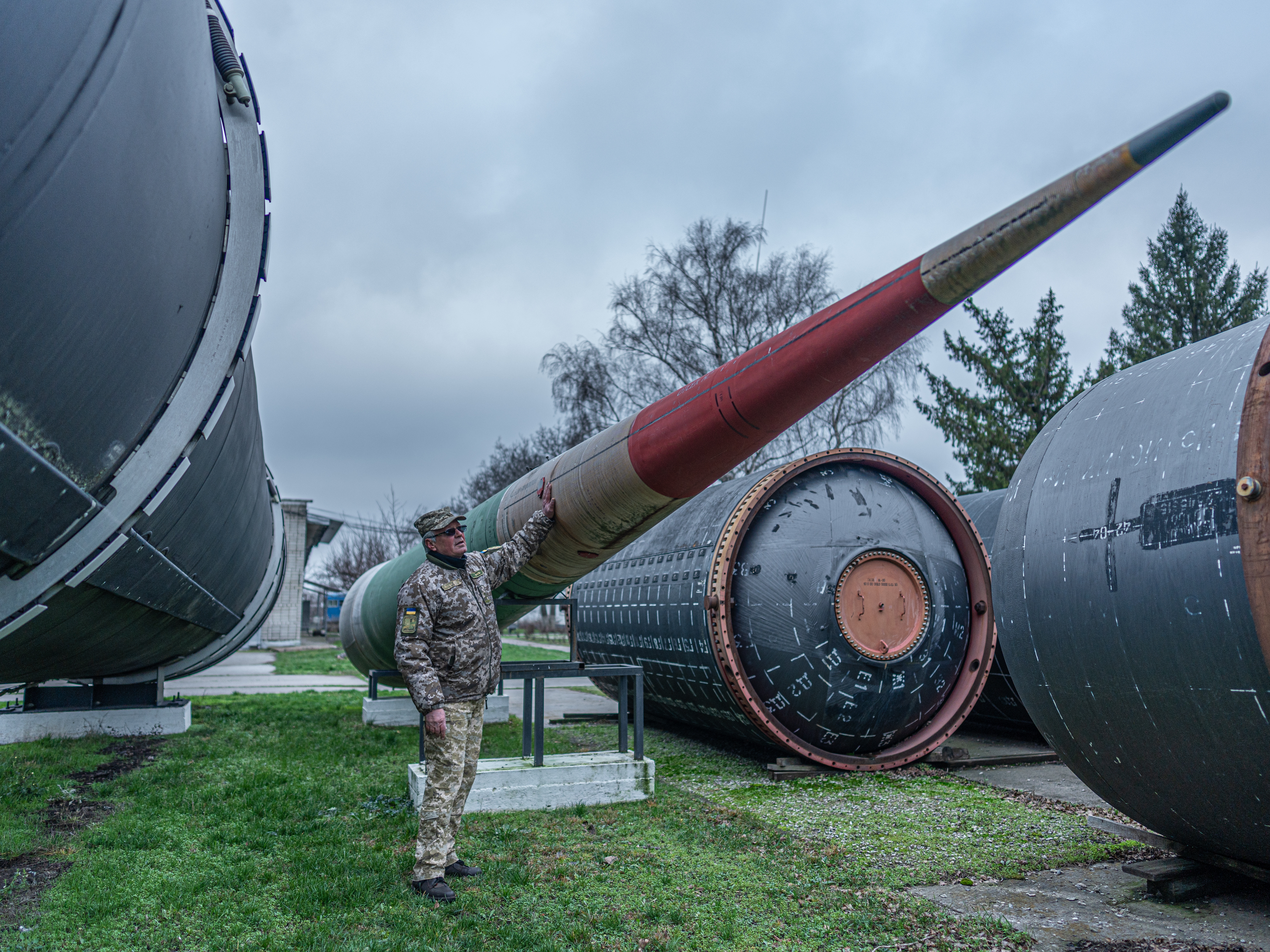 caption: Hennadiy Vladimirovitch Fil, 65, former deputy commander of the Soviet Union's 309th Missile Regiment, stands near an old Soviet air defense missile at the Museum of the Strategic Missile Forces, where he is now a guide, on Dec. 5.