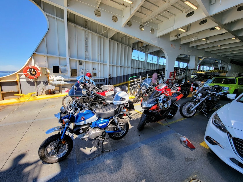caption: Motorcycles of all makes and models parked at the front of a ferry.