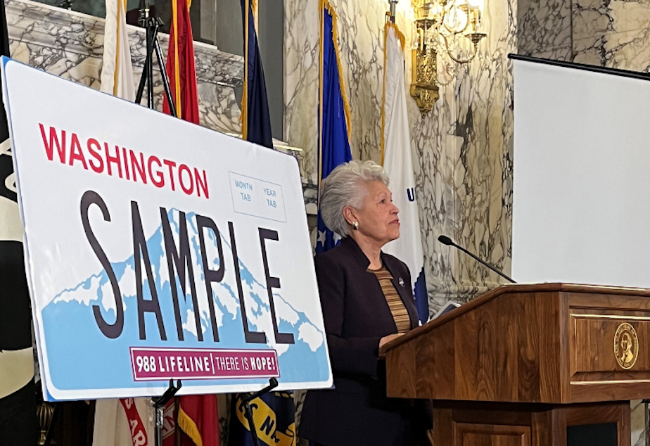 caption: Washington state Department of Veterans Affairs Director Alfie Alvarado-Ramos speaking at an unveiling ceremony in Olympia on Tuesday, Nov. 29, 2022. The department debuted a new sticker for license plates that feature a suicide hotline. 
