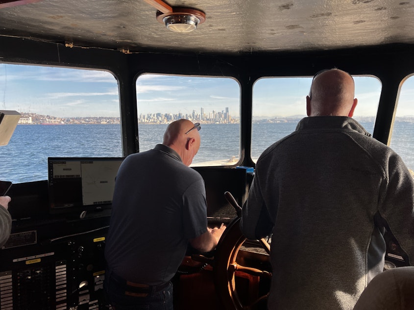 caption: Two of the Seablazer's captains review charts, with downtown Seattle in the distance.