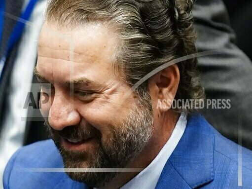 caption: Mark Brnovich smiles as he talks with people on the floor of the Arizona House of Representatives, at the Arizona Capitol in Phoenix.