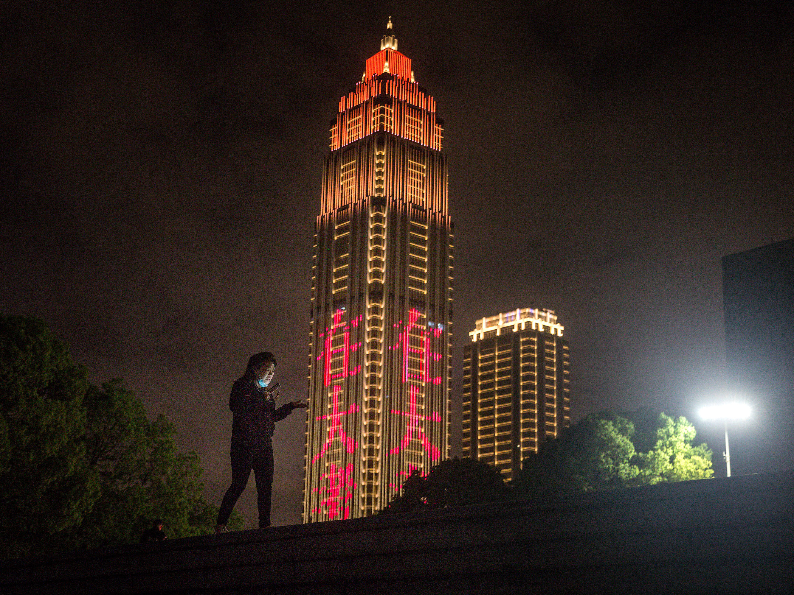 caption: A resident talks on the phone while walking in Jiangtan park after its reopening in March in Wuhan, Hubei province, China. The new coronavirus pandemic felt thousands of miles away, until it didn't. As cases in the U.S. skyrocketed, many noticed a shift — from watching the headlines, to watching what we touch.